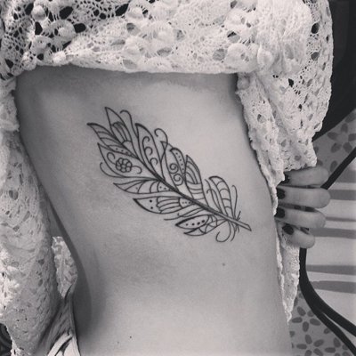 Tatouage plume sur les côtes avec des petits oiseaux noirs